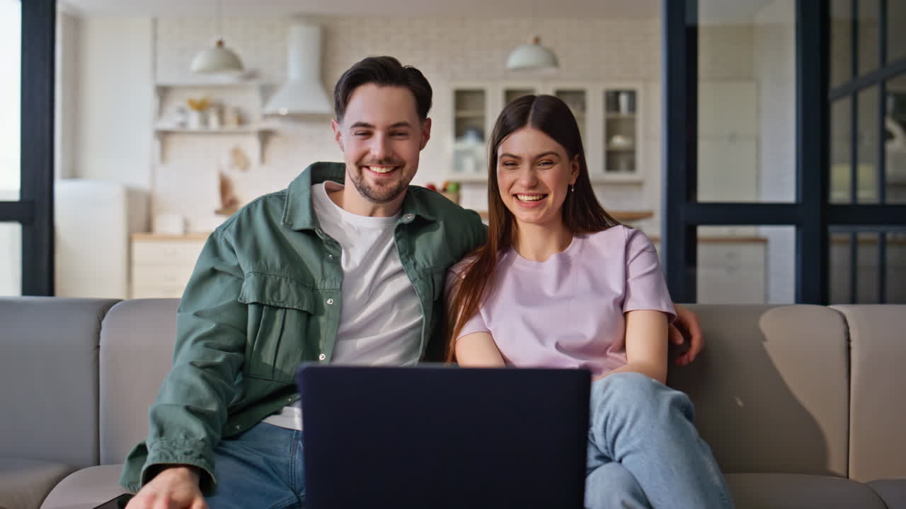 Overjoyed pair making video conference greeting laptop emotionally. Fun couple