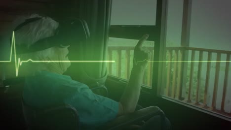 Animation-of-glowing-green-heart-rate-monitor,-over-senior-woman-in-wheelchair-using-vr-headset