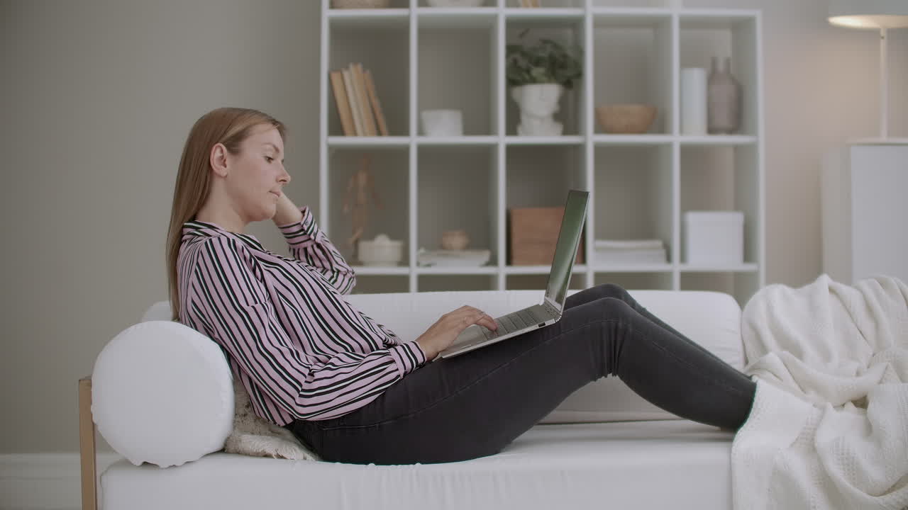 코로나 바이러스 팬데으로 인해 자율 격리 기간 동안 젊은 여성은 집에 머물고 인터넷과 온라인 채팅을 가진 노트북을 사용하고 있습니다.