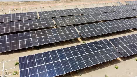 panorámica aérea baja a la izquierda que muestra matrices fotovoltaicas polvorientas y limpias en la planta de energía fotovoltaica solar africana en construcción