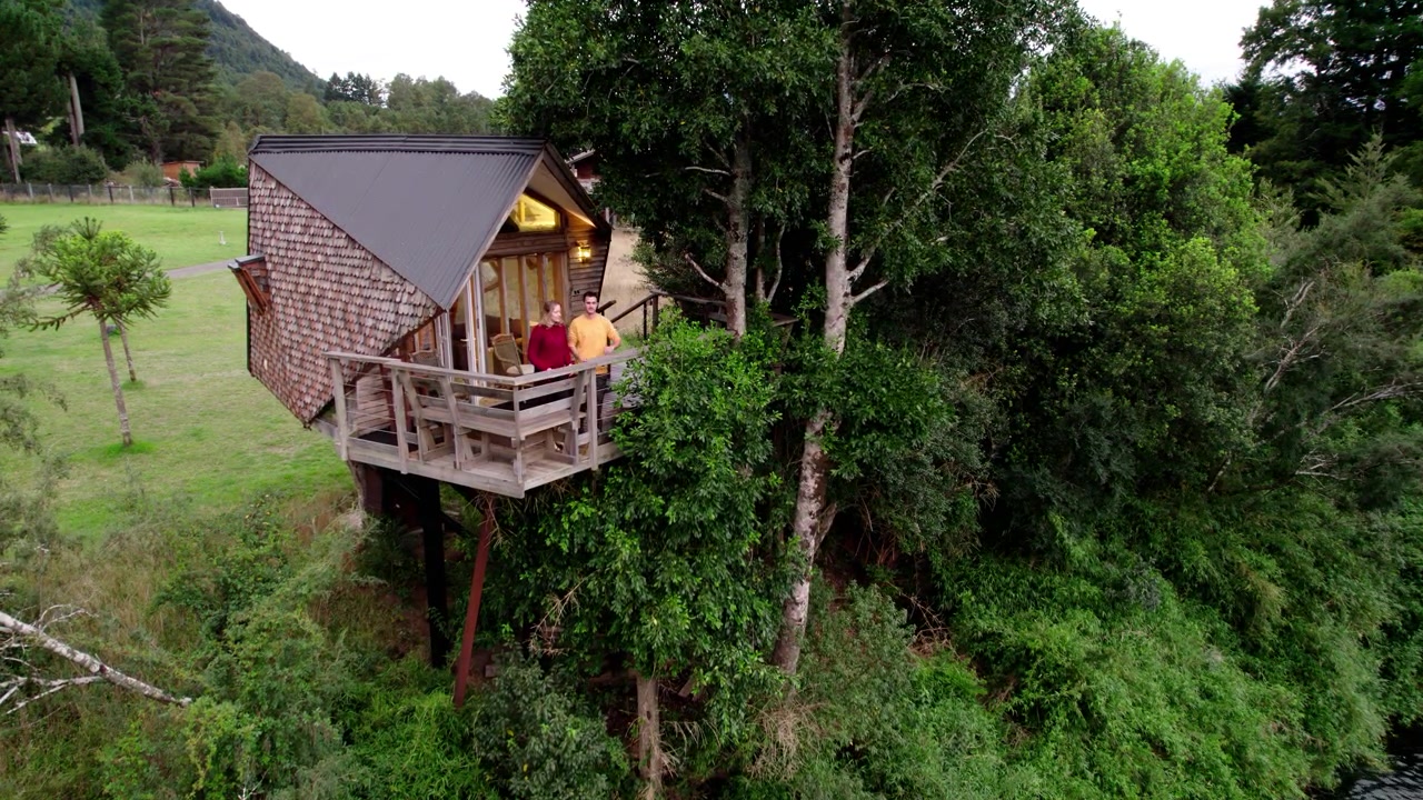 Una coppia che si rilassa in una sistemazione unica in casa sull'albero costruita tra alberi verdi e lussureggianti vicino a un fiume sereno in un ambiente tranquillo