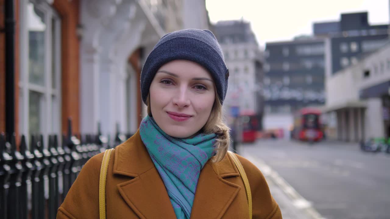 Happy cheerful positive young Caucasian woman in the streets of London, looking the camera and smiling, slow motion