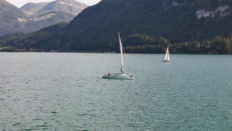 sailboat gliding on a calm lake surrounded by mountains and lush forests, peaceful and serene