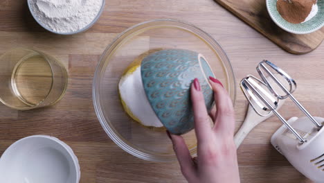 adding a cup of white sugar to fresh eggs in a bowl