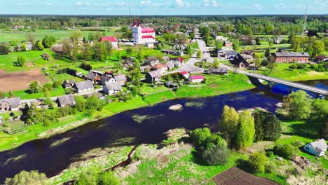 a picturesque lithuanian village with green fields and a river, aerial view
