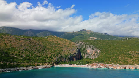 avión no tripulado en movimiento hacia adelante disparado sobre los turistas que se agolpan a lo largo de la aislada playa de gjipe en dharmi, albania en un brillante día soleado