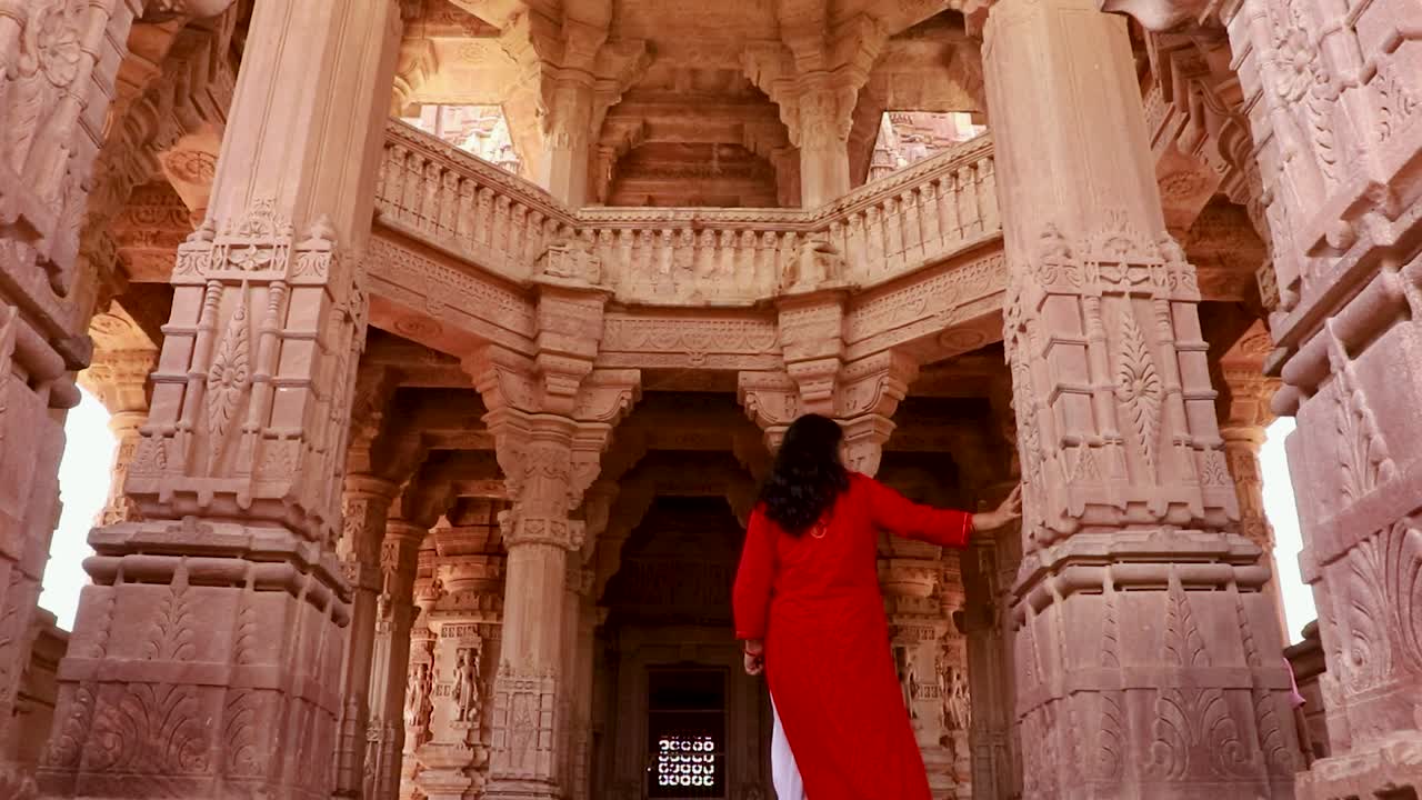 chica joven caminando en el antiguo templo tallado en piedra desde el ángulo de atrás en el día