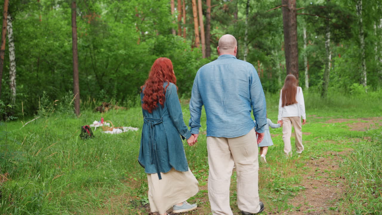 Autumn lover family strolls through lush forest, kids holding hands walking ahead while parents follow behind lovingly, surrounded by greenery, and soft sunlight creating peaceful outdoor atmosphere