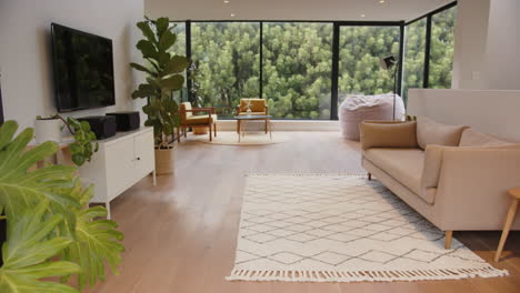 modern living room with large windows, cozy sofa, and indoor plants, copy space