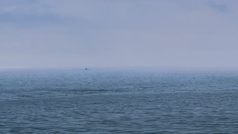 mar tranquilo con barco solitario con cielo nebuloso con olas que se elevan y caen suavemente