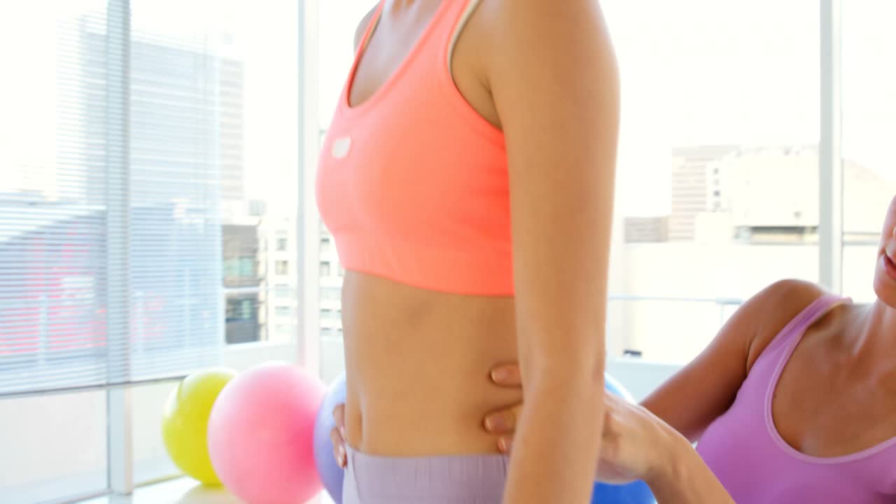 Istruttrice di fitness che preme sulla schiena della sua cliente