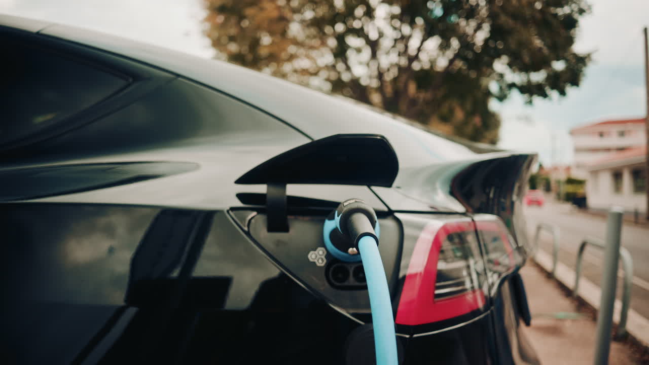 Şık siyah bir elektrikli arabaya bağlı bir şarj cihazının yakın çekim görüntüsü