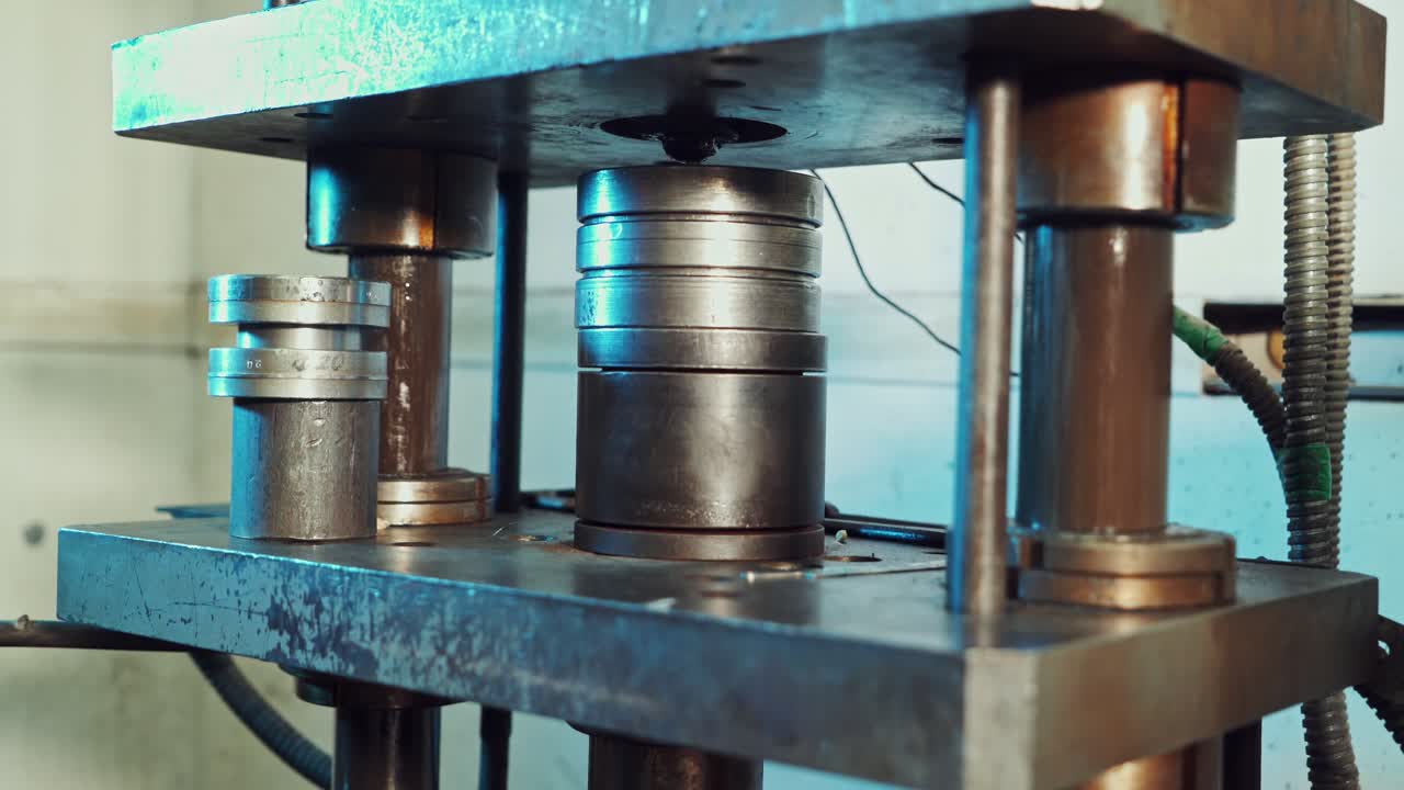 Close up shot of a punch press forming metal parts in the industrial factory. Worker puts some parts to the press mold.