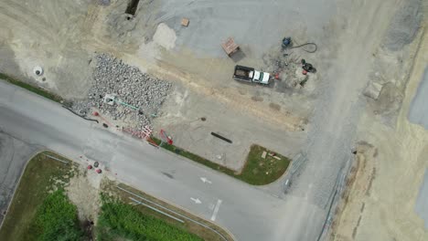 vista aérea de equipos de construcción pesados que trabajan en el sitio de construcción cerca de una carretera solitaria en un día soleado