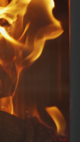 video vertical de primer plano llamas de fuego troncos en la estufa de leña en casa 4