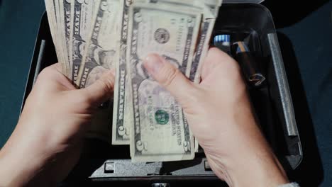 the cashier recounts the money in us dollars. on a background of a portable cash box