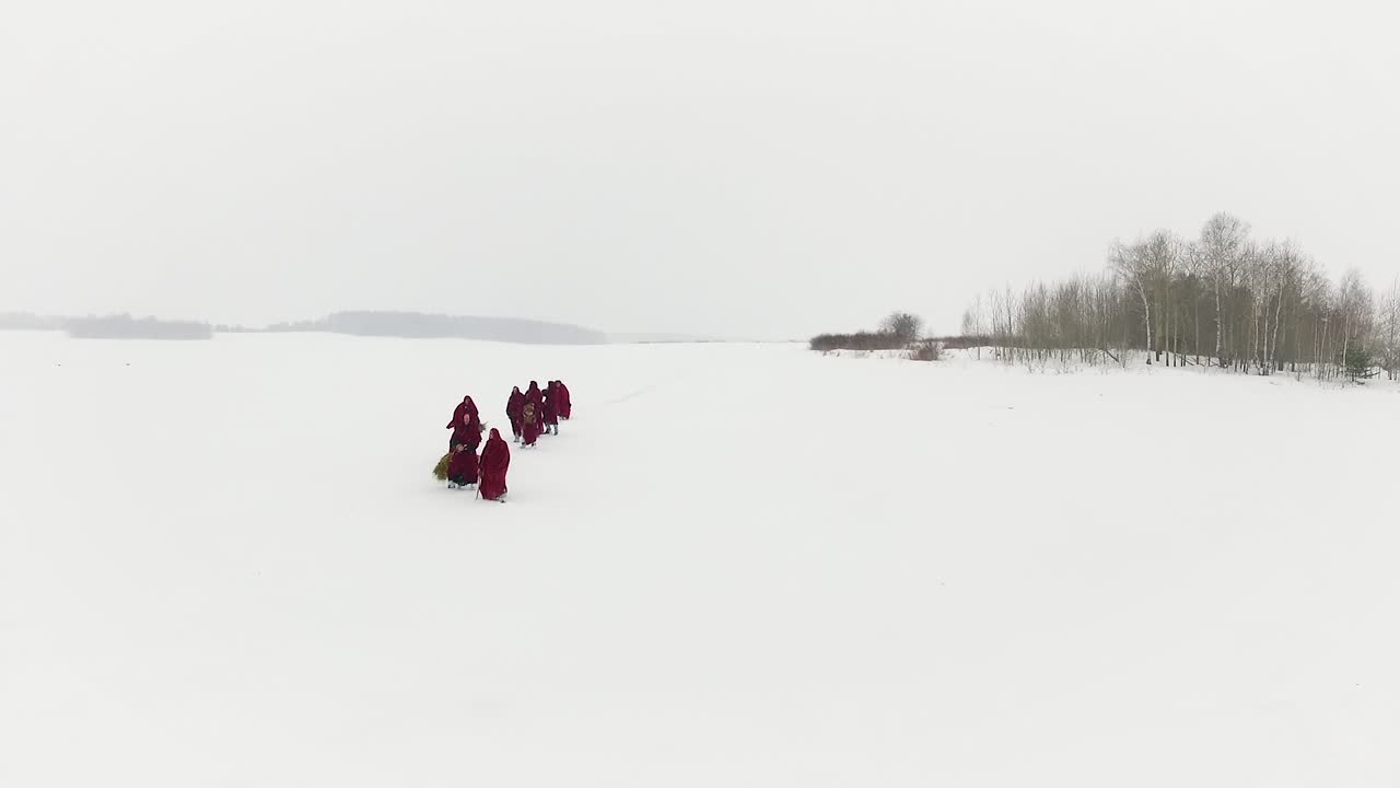 Group in Red Robes Walking Across Snowy Landscape