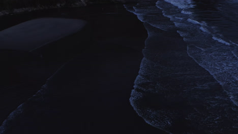 Ocean-waves-rolling-towards-sandbar,-cliffs-on-Oregon-Coast,-tilt-up,-slow-motion