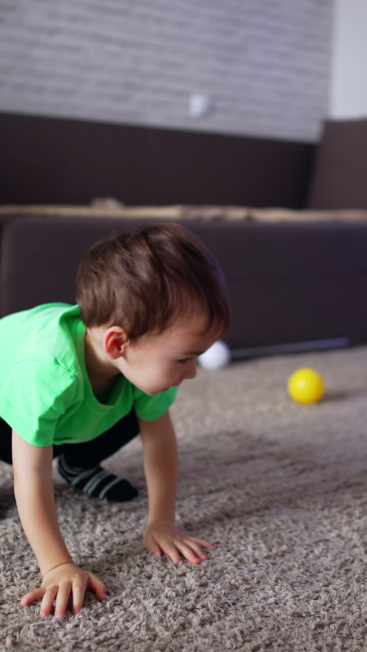 Adorable cheerful kid crawling by the floor. Happy toddler playing in his room at home. Vertical video