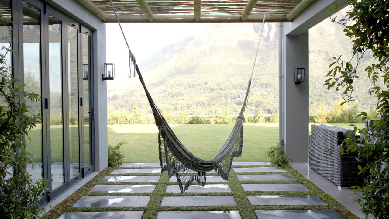A hammock hanging between two pillars on patio with mountains in background