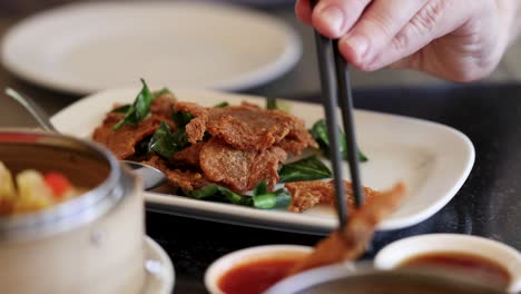 chopsticks picking fried pork from a plate