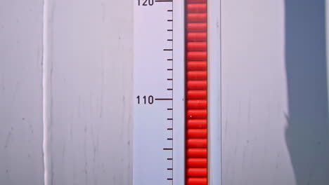 a close-up dolly-up shot follows a rising red indicator on a level gauge, showing a large industrial storage tank at a gas facility in latvia being filled with fuel or natural gas