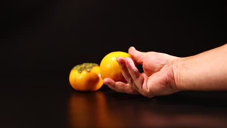 a hand picks and holds persimmons