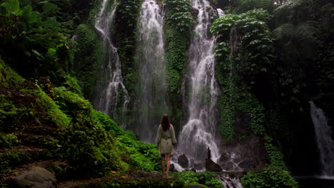 female tourist mesmerized by breathtaking banyu wana falls down lush foliage