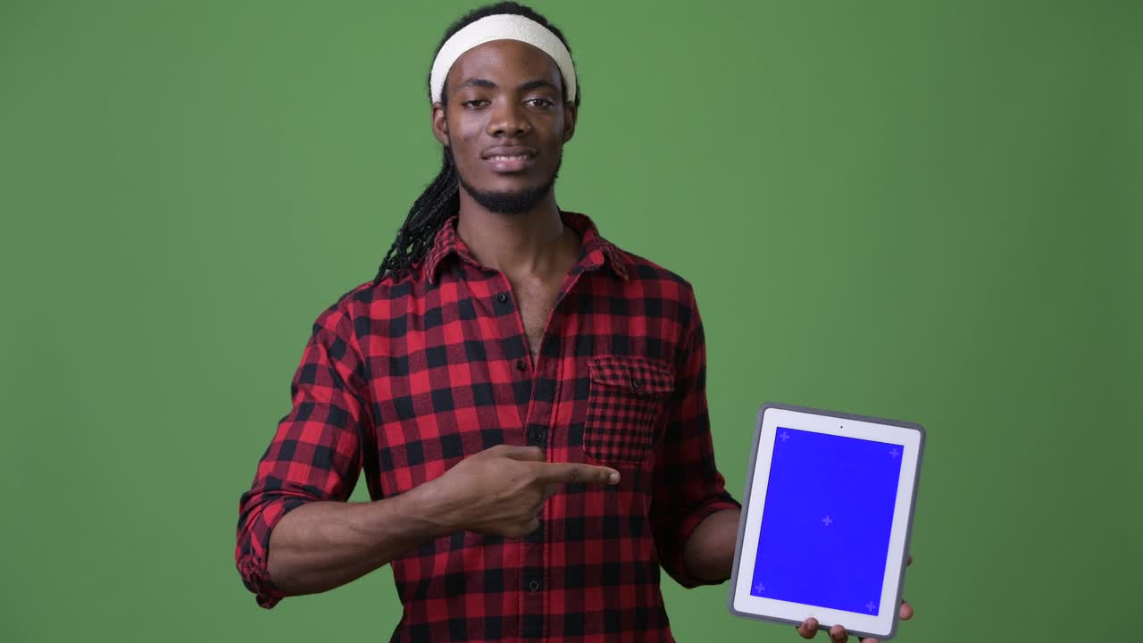 Young handsome African man with dreadlocks against green background