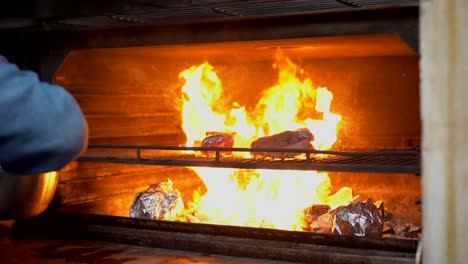 latin chef restaurant put picanha inside charcoal grid grill oven hot fire flames slow motion