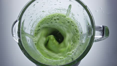 closeup green vegetables mix in blender top view. healthy vegan smoothie.