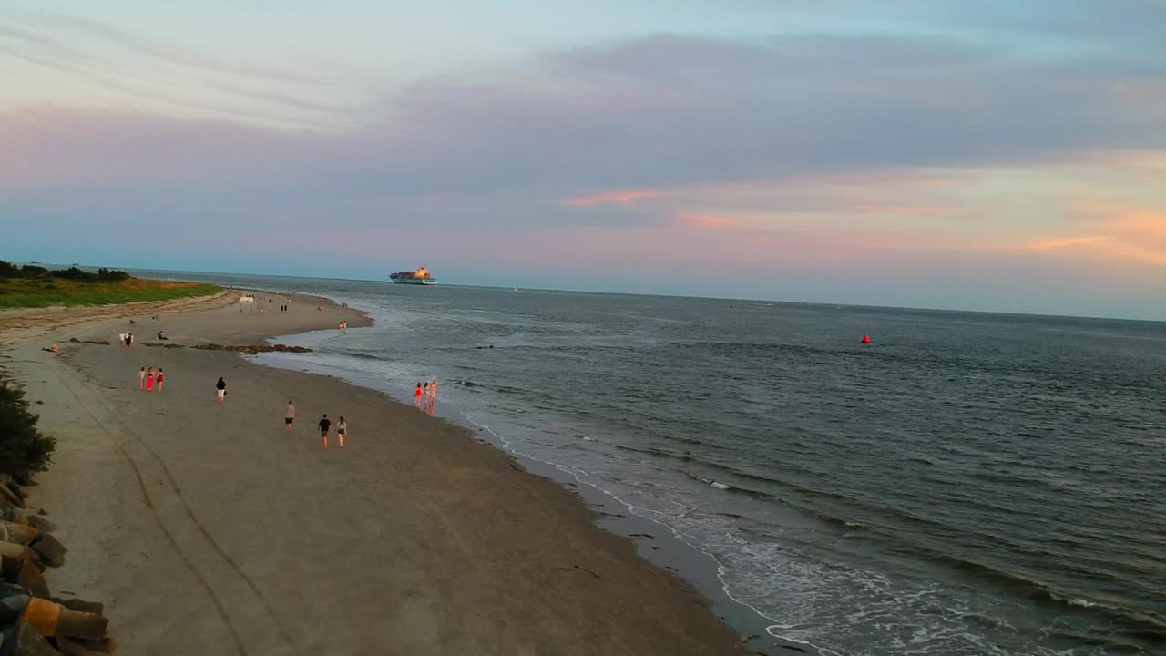 barco de contenedores en el océano desde la vista de drones en la playa, gente caminando