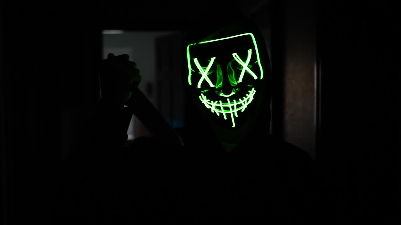 un asesino aterrador con una máscara genérica de halloween persiguiendo a una víctima de asesinato asustada con un cuchillo en cámara lenta