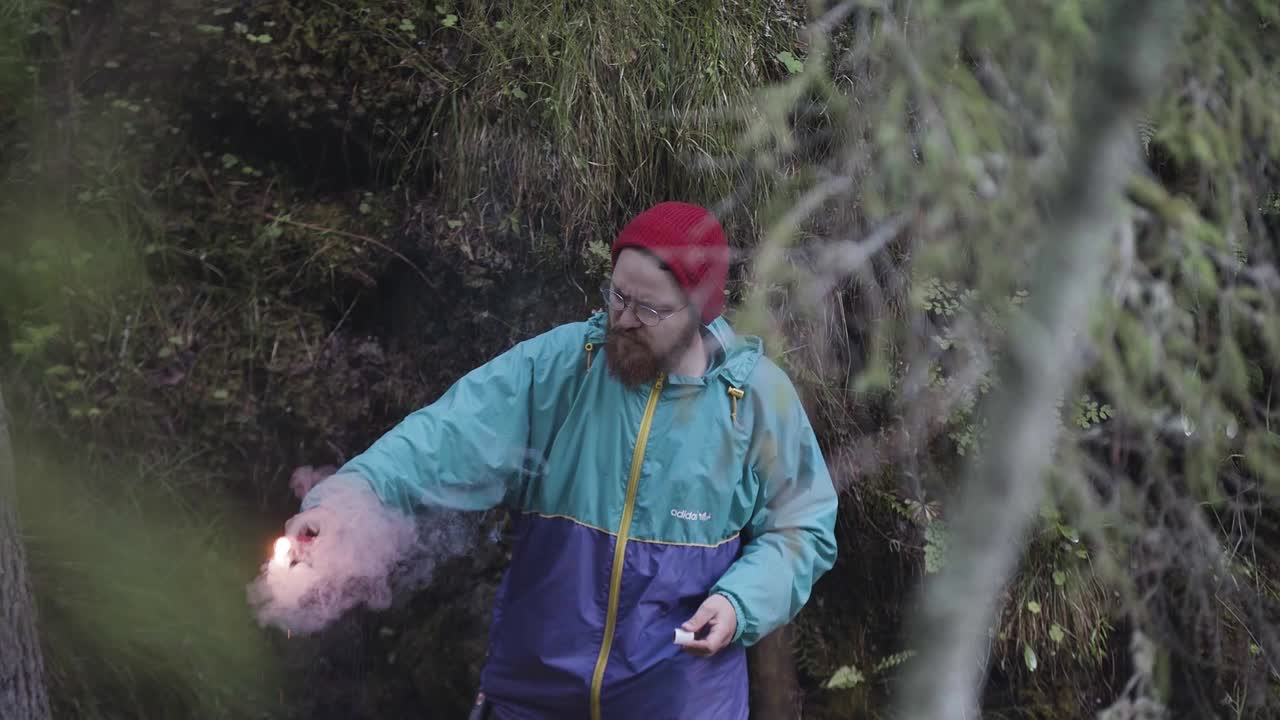 Mand med rød røggranat i en skov