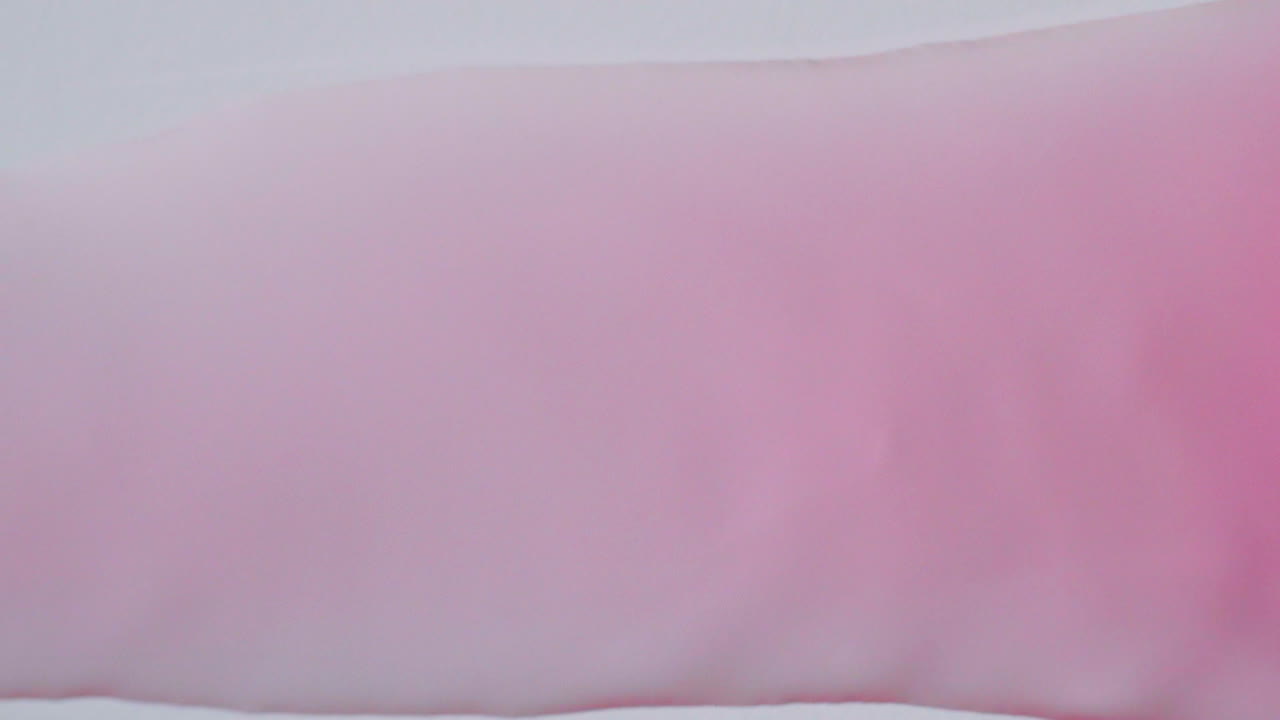 розовая вода в пузырьках, текущая справа налево на фоне белой бумаги