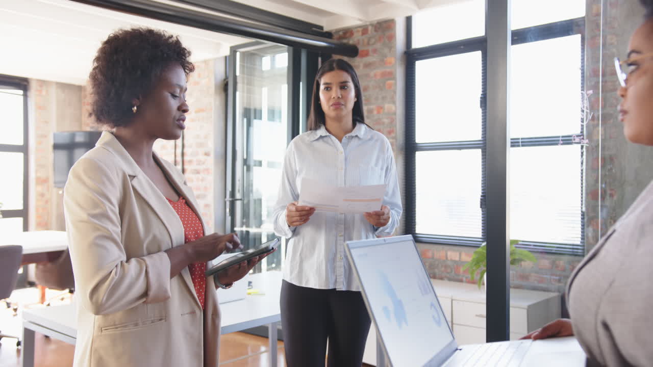 Discussing business strategy, diverse team collaborating with documents and laptop in office setting