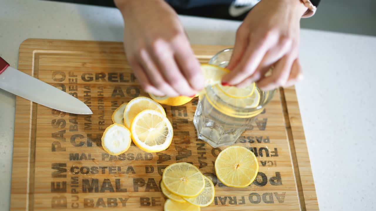 Joven deportista prepara agua con limón en la cocina. Estilo de vida saludable. Agua desintoxicante y vitaminada. Concepto de dieta.