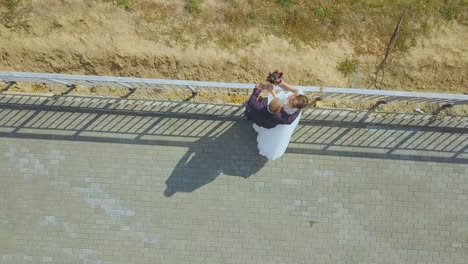 una pareja recién casada se besa cerca de la barandilla sobre la vista superior de la colina