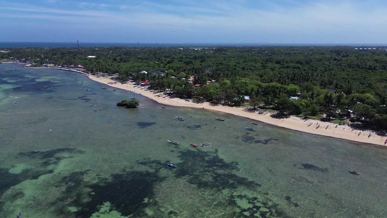 Aerial view of a tropical island coastline with white sand beach clear ocean water and dense green vegetation creating a pristine and untouched landscape on Bantayan Island Philippines Southeast Asia