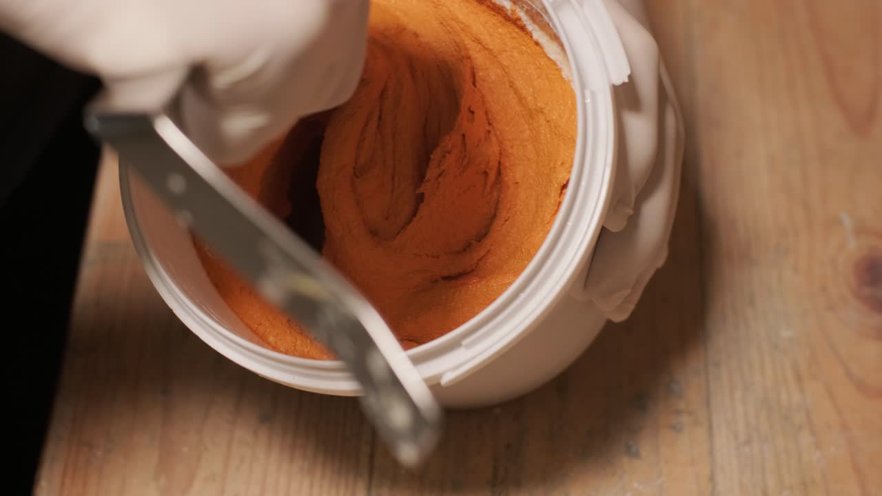 한 노동자 가 벽 을 칠 하기 위해 페인트 를 는다