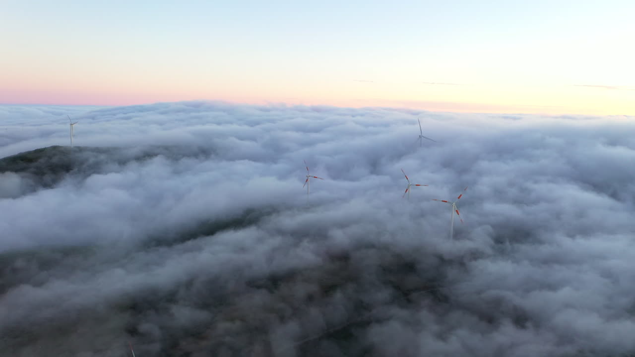 포르투갈 마데이라 섬의 일몰에 풍력 터빈이 있는 들판을 가로질러 움직이는 낮은 구름의 드론 항공 영상