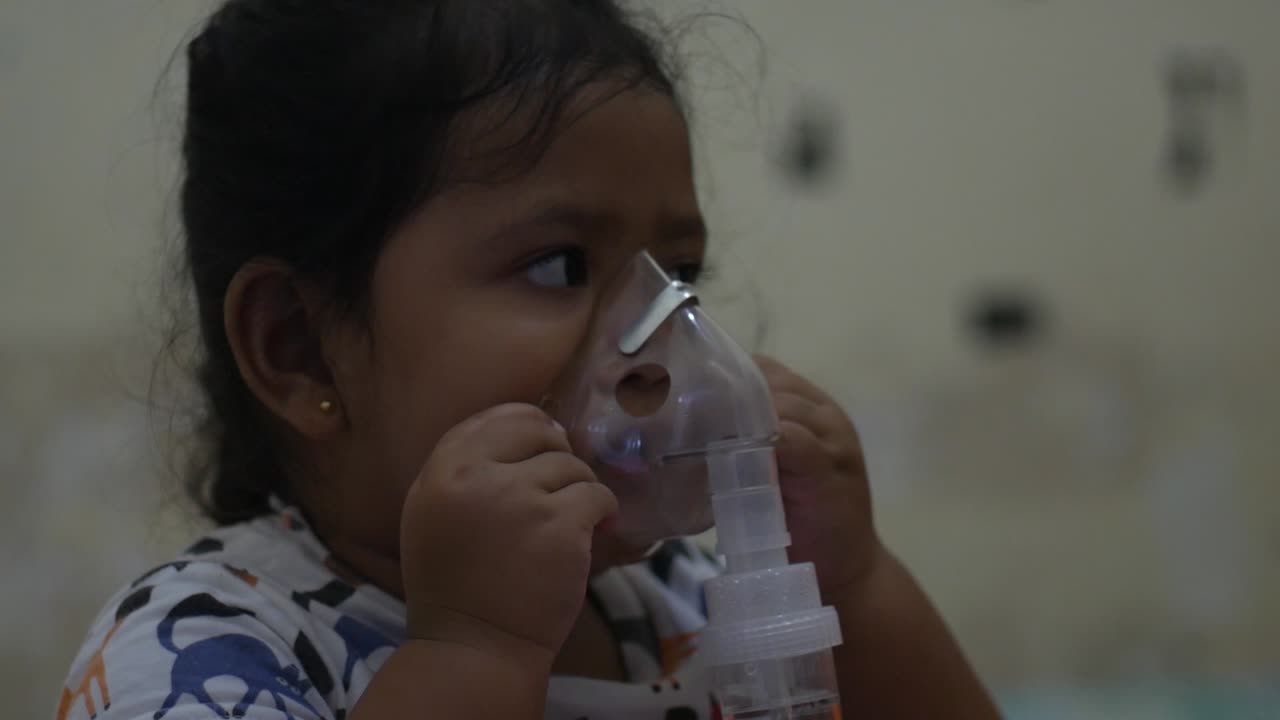 Little girl in a mask, treatments respiratory tract with a nebulizer at home