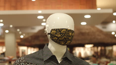 Maniquí-Masculino-Con-Máscara-De-Tela-Impresa-Batik-Exhibida-Dentro-De-Un-Centro-Comercial---Primer-Plano