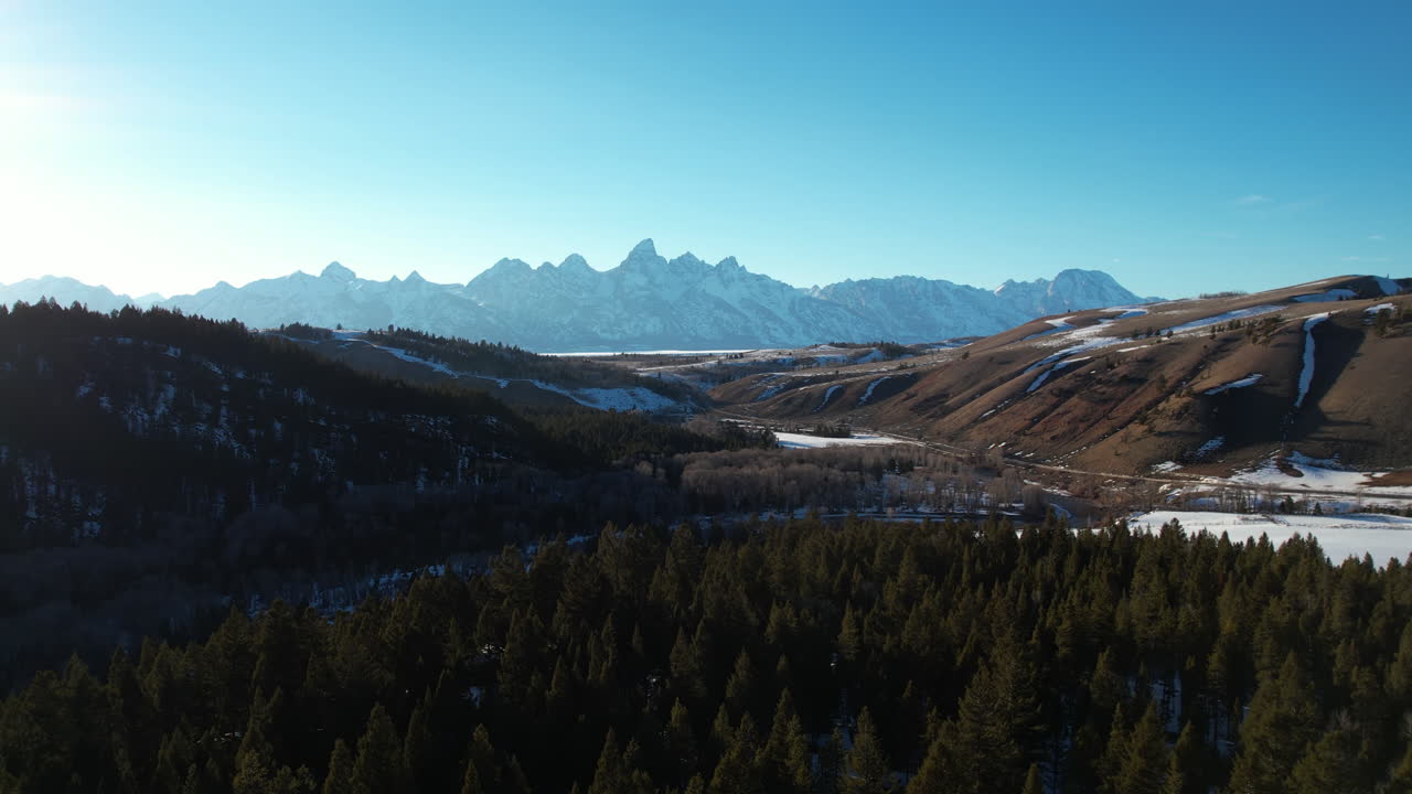 Vista aerea della catena montuosa del Teton in una soleggiata giornata di tardo autunno, con pineta e cime innevate all'orizzonte