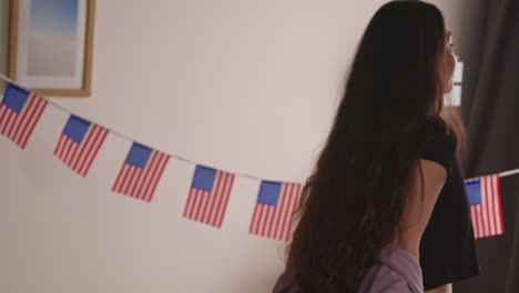 mujer en casa poniendo estrellas americanas y banderas de rayas en el sofá para la fiesta celebrando el 4 de julio día de la independencia 2