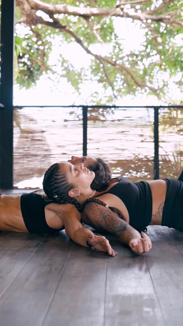 Duas mulheres praticando ioga em dupla em um estúdio ao ar livre
