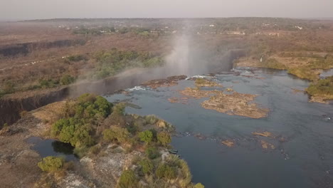 orbiting aerial of famous victoria falls with subtle rainbow in mist