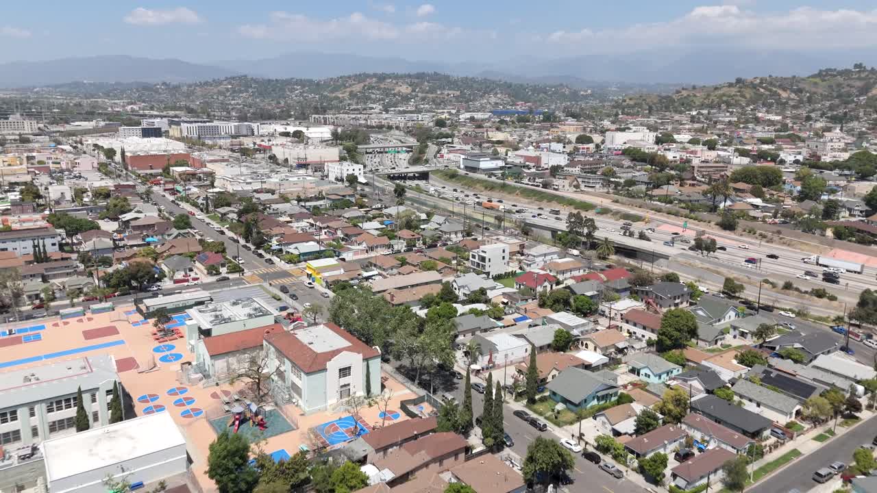 Aerial Flyover Of Suburban Streets In East Los Angeles neighborhood with Busy Hollywood Freeway.