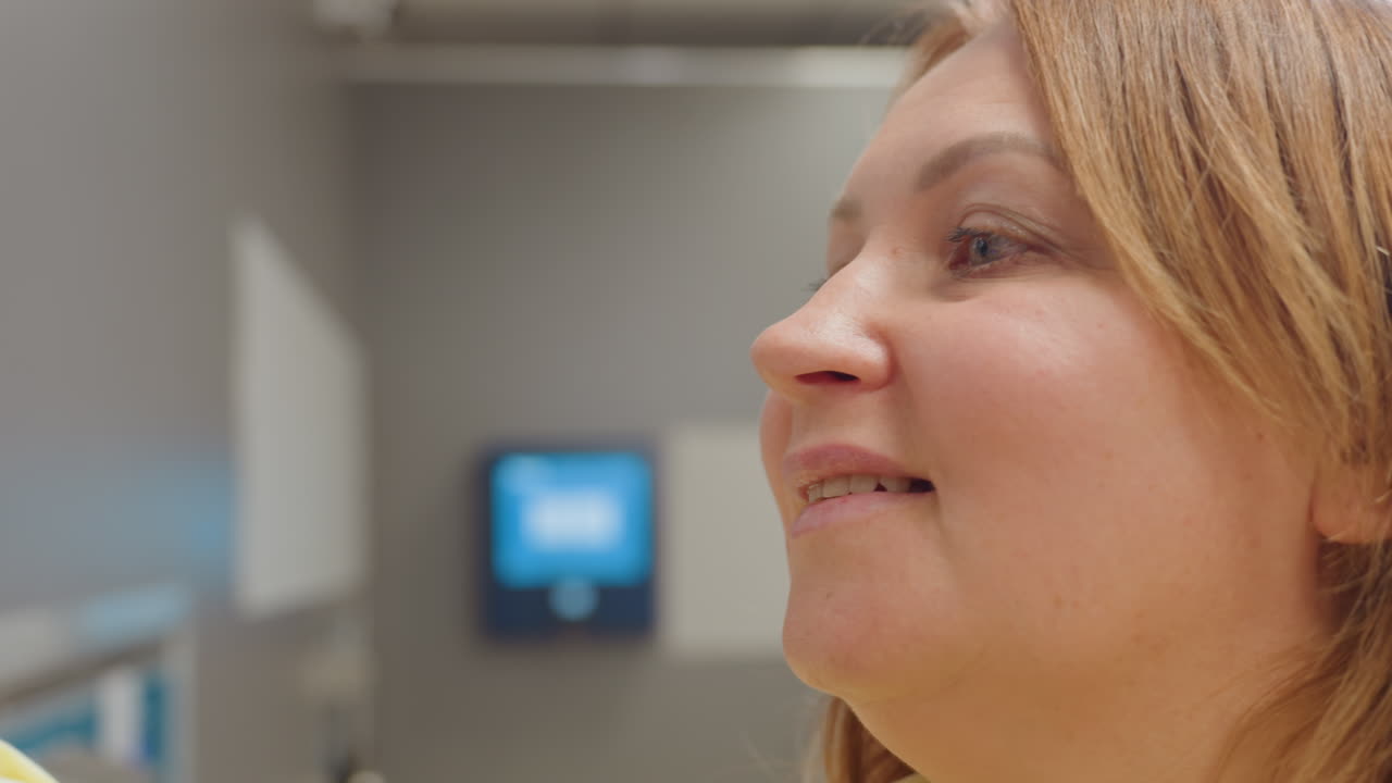 Close up of joyful mom smiling while wiping surface, cheerful expression showing happiness and satisfaction during cleaning work inside modern laundry facility with bright lighting