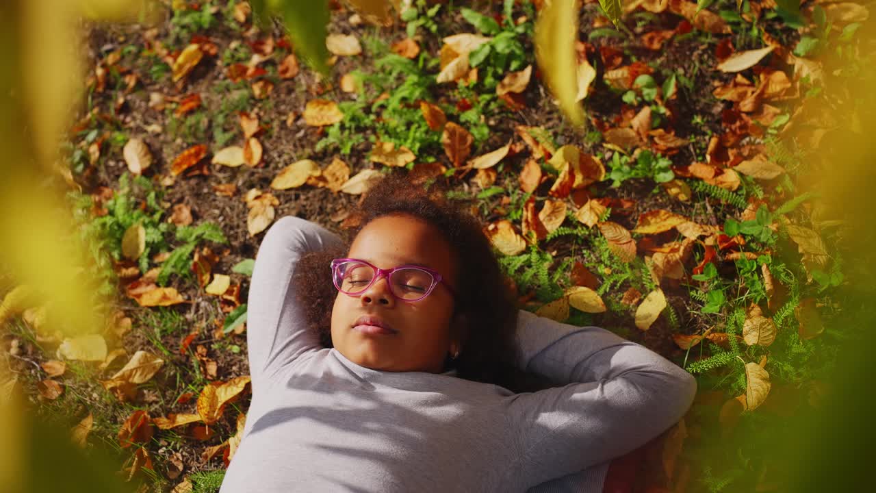 Peaceful Young Girl Resting on Ground with Autumn Leaves
